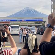 Visitors take a photo of Mount Fuji in front of a store (Kyodo News via AP)