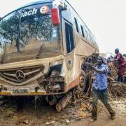 People try to move a bus that was washed away in Kenya (Patrick Ngugi/AP)